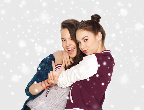 happy teenage girls hugging and showing peace sign - 写真・画像