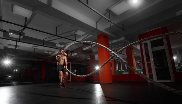 Fitness man working out with battle ropes at a gym - Foto, Bild