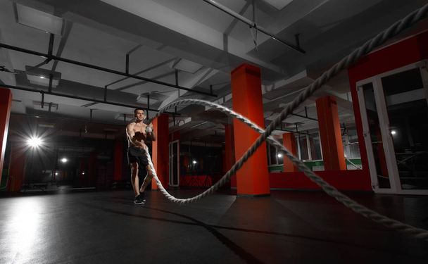 Fitnessmann trainiert mit Kampfseilen im Fitnessstudio - Foto, Bild