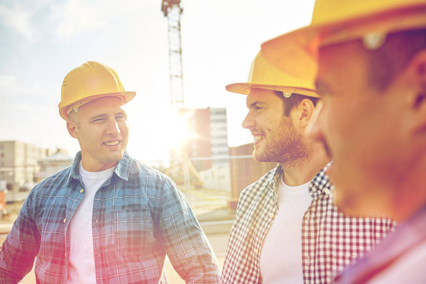 group of smiling builders in hardhats outdoors - 写真・画像