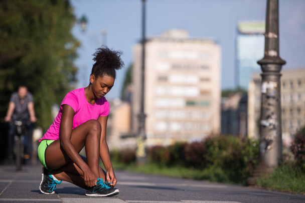 African american woman runner tightening shoe lace - 写真・画像