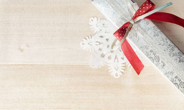 Wrapped gift and paper snowflakes on wood. Christmas siver red b - Φωτογραφία, εικόνα