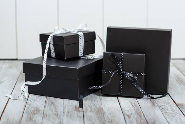 Black gift boxes over wooden background. - Zdjęcie, obraz