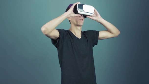 Young man with purple bangs using vr glasses headset doing gestures looking around - 映像、動画