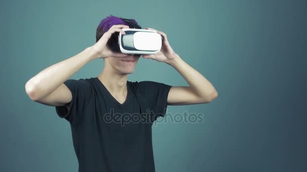 Young man with purple bangs using vr glasses headset doing gestures looking around - Video