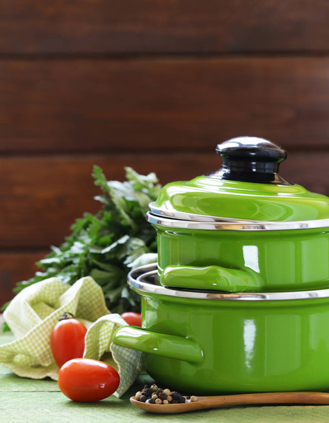 Зелений горщик для приготування їжі та інгредієнти для супу або тушкованого на сільському фоні
 - Фото, зображення