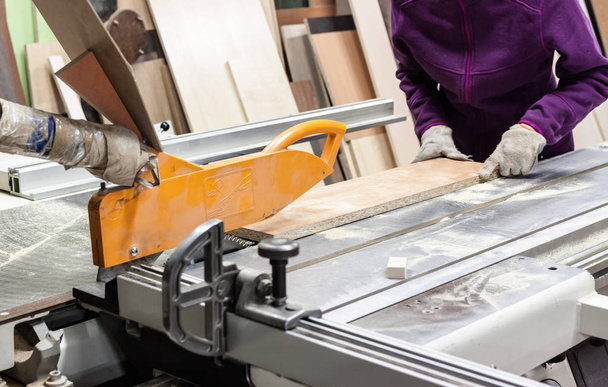 Women worker using saw machine to make furniture at carpenters workshop. - Foto, Bild
