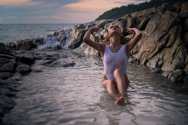 Hermosa mujer entre rocas en la playa tropical
 - Foto, imagen