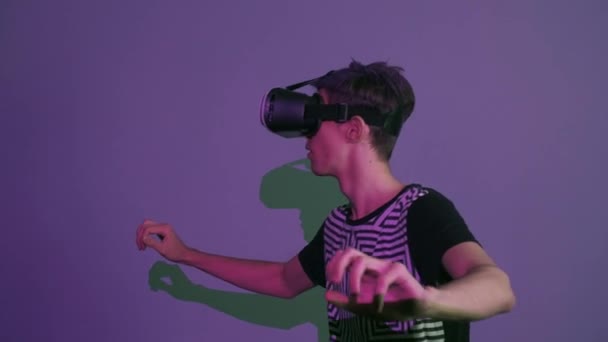 Young man with purple bangs using vr glasses doing gestures looking around purple background - Video