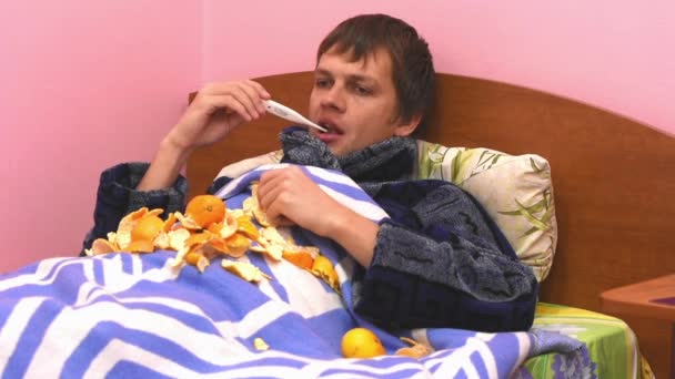 Um homem doente deitado na cama e medirá a temperatura de um termômetro eletrônico
 - Filmagem, Vídeo