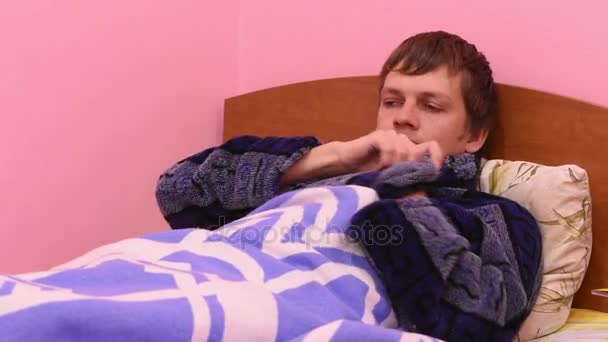 Chory człowiek, leżąc w łóżku, pomiar temperatury i zjada mandarynki - Materiał filmowy, wideo