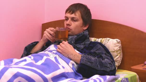 Chory leży w łóżku i pić gorącą herbatę - Materiał filmowy, wideo