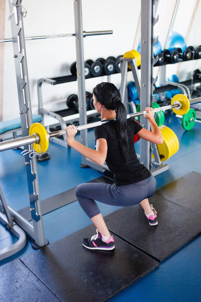 Long hail girl doing squats with a barbell - Foto, Imagen