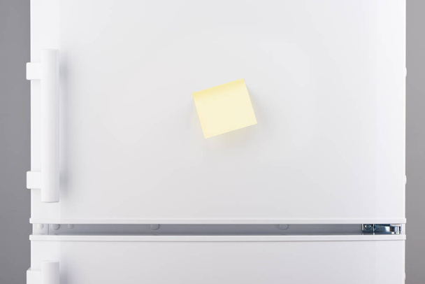 Blank light yellow sticky paper note on white refrigerator - Фото, зображення