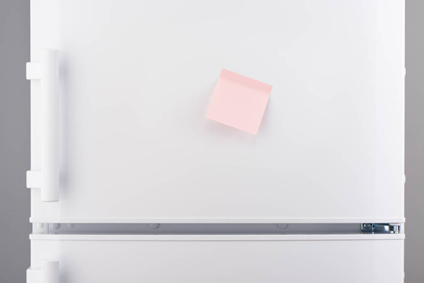 Blank light pink sticky paper note on white refrigerator  - Foto, imagen