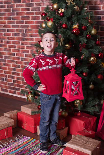 Chłopiec stoi na podłodze obok prezenty i drzewa - Zdjęcie, obraz