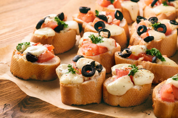 Baked toasts with mozzarella, tomatoes, olives and garlic. - Foto, Imagem