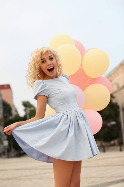 Beautiful young woman holding air balloons on street - Фото, зображення