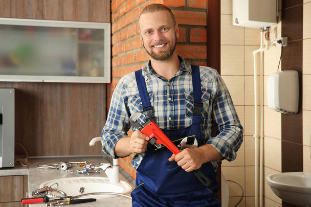 Portrait of handsome plumber with pipe wrench - Fotó, kép