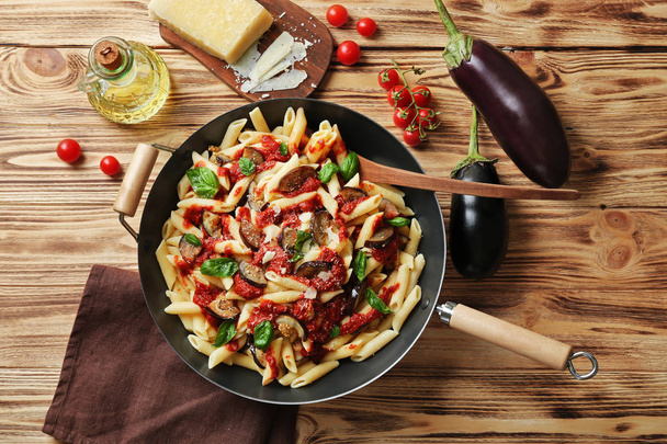 Pan with tasty macaroni, products and napkin on wooden table, top view - Foto, immagini