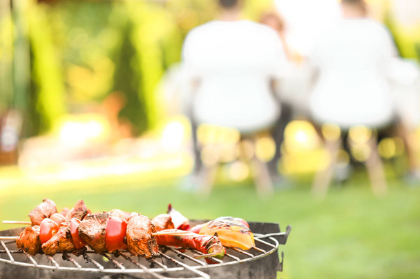 Tasty meat and vegetables on barbecue grill against blurred background, close up view - Foto, Bild