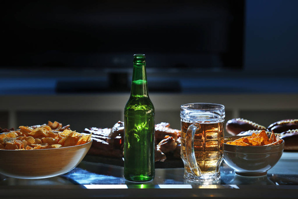 Tasty snacks and beer on kitchen table against blurred background - Photo, Image