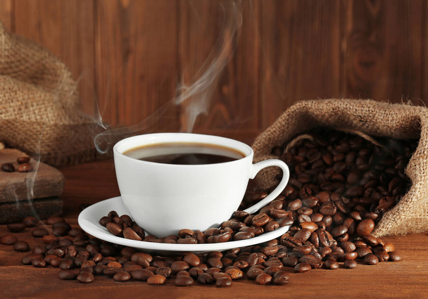 Cup of fresh coffee and sack with beans, closeup - Фото, зображення