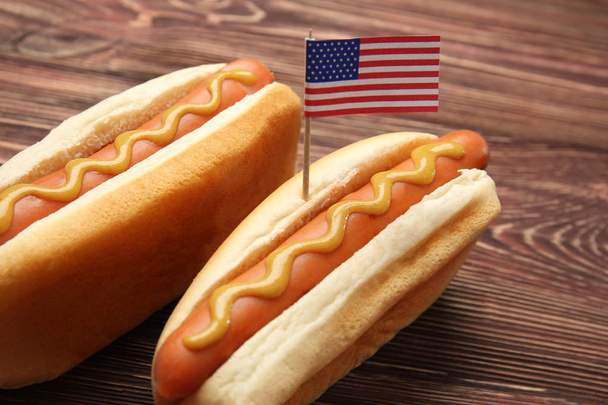 Hot dogs with mustard and small USA flag on wooden background - Fotoğraf, Görsel