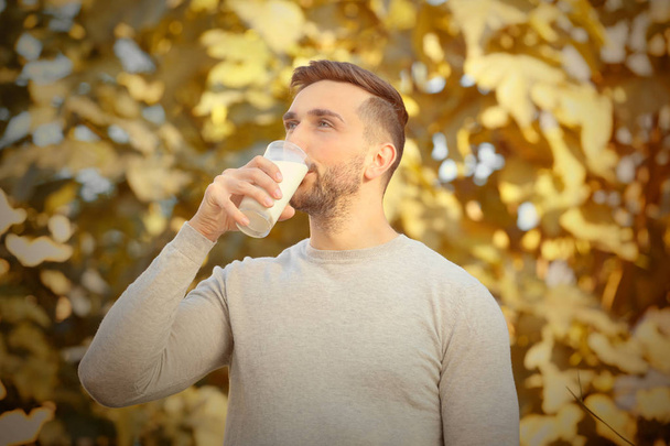 Young man with glass of fresh milk outdoor - Foto, immagini