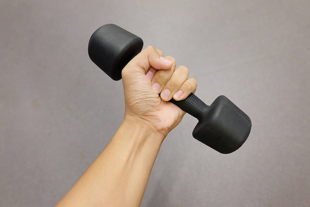 Hands holding dumbbells in sport club or gym and fitness room. - Photo, image