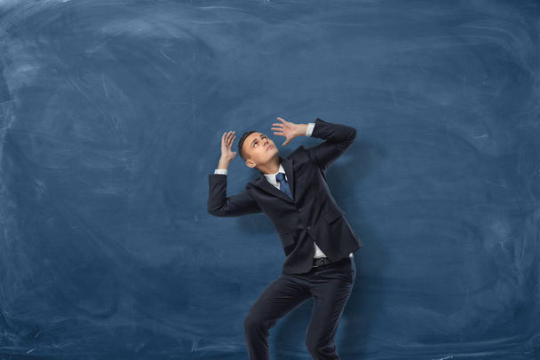 Businessman standing in desparate pose on blue chalkboard background - Foto, Bild