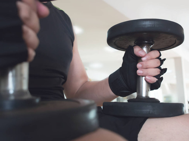 man hands wear gloves with dumbbells at the gym. - Photo, Image