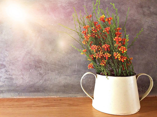 Plastic flower in jar on wood table with stucco wall background - Photo, Image