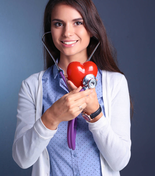 Doctor woman with stethoscope examining red heart - Фото, изображение