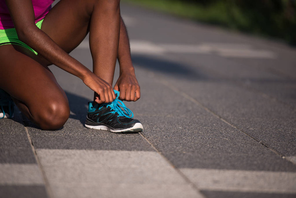African american woman runner tightening shoe lace - Foto, Bild