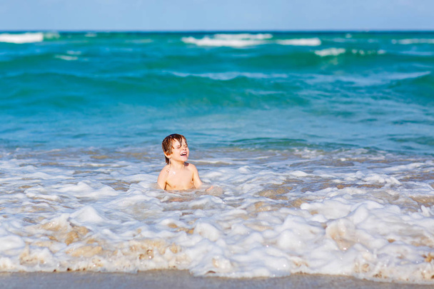 маленький блондин мальчик весело проводит время на пляже океана во Флориде
 - Фото, изображение