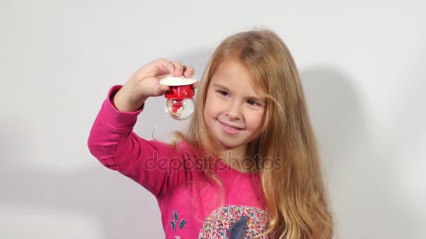 Schattig klein meisje sneeuwbol te houden. Meisje kijkend naar de kerst souvenir. Weinig sneeuw Globe in handen van het kind.  - Video