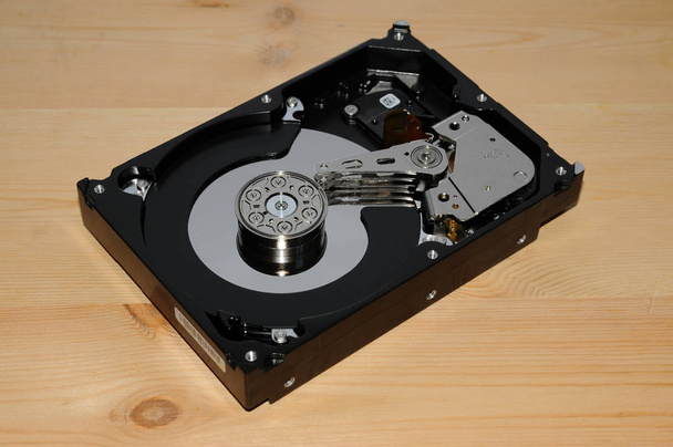 Unidad de disco duro de computadora abierta sobre fondo de madera
 - Foto, imagen