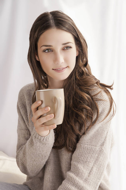 beautiful woman drinking coffee, sitting by window - Zdjęcie, obraz