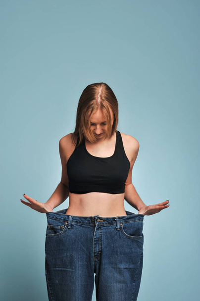 Fit young woman in loose jeans - Fotoğraf, Görsel