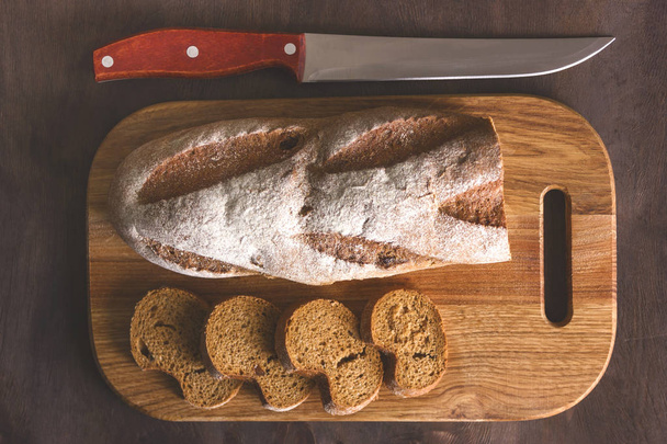 Pan negro en una tabla de cortar con un cuchillo
  - Foto, imagen