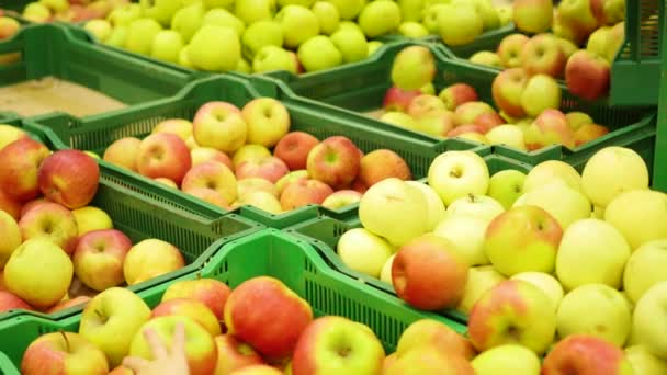 dělník v supermarketu dá ovoce jablka do zásobníků - Záběry, video