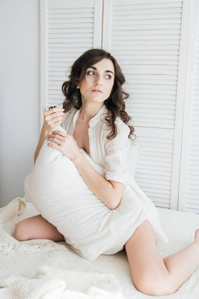 Woman in underwear sitting on the bed hugging a pillow - Photo, Image