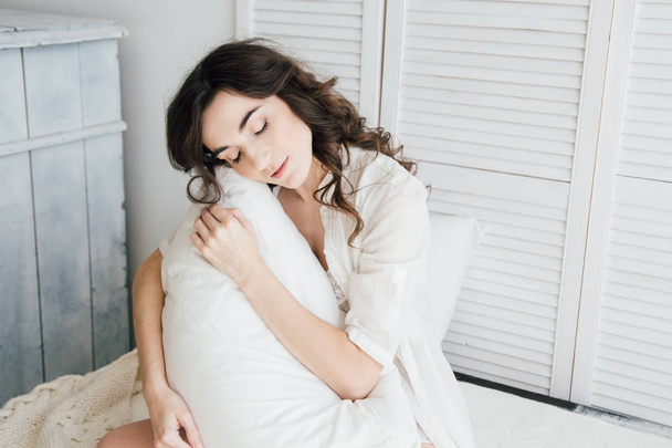 Woman in underwear sitting on the bed hugging a pillow - Fotó, kép