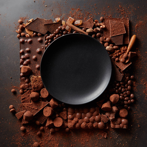 frame of different chocolates with black plate - Φωτογραφία, εικόνα