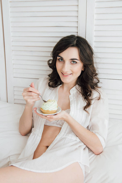 Girl eats cake for Breakfast in bed  - Valokuva, kuva