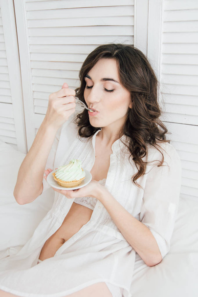 Girl eats cake for Breakfast in bed  - Fotoğraf, Görsel