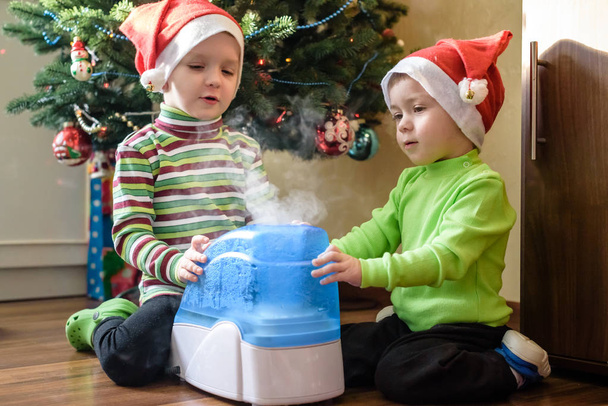two adorable boys playing with working humidifier, waiting for x-mas - Photo, Image