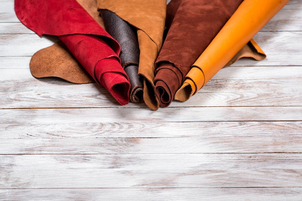 Brightly colored leather in rolls on white wooden background. Leather craft. Copy space. - Photo, Image