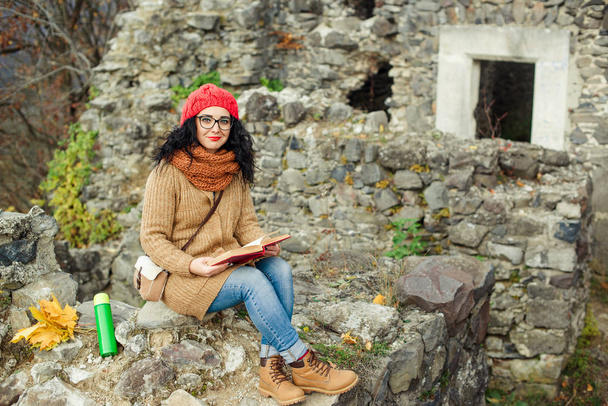 Krásná dívka číst knihu poblíž starého hradu. Podzimní čas. - Fotografie, Obrázek